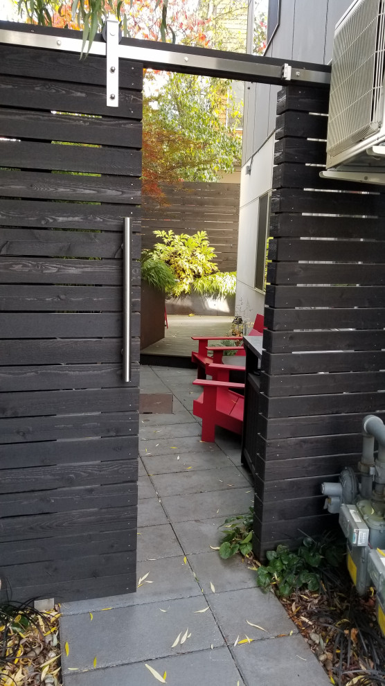 Foto på en liten funkis trädgård i skuggan längs med huset på sommaren, med marksten i betong