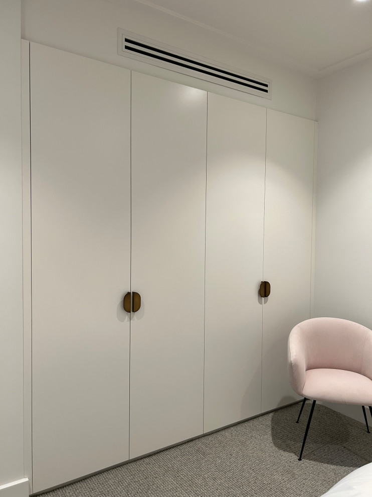 Cette photo montre une armoire encastrée moderne de taille moyenne pour une femme avec un placard à porte plane, des portes de placard blanches, moquette et un sol gris.