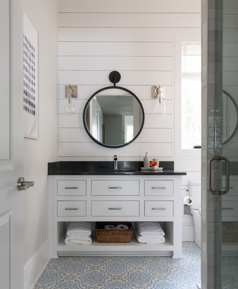 Photo of a mid-sized beach style kids bathroom in Dallas with flat-panel cabinets, white cabinets, an alcove shower, a two-piece toilet, white tile, porcelain tile, white walls, ceramic floors, an undermount sink, engineered quartz benchtops, blue floor, a hinged shower door, black benchtops, a single vanity, a built-in vanity and planked wall panelling.