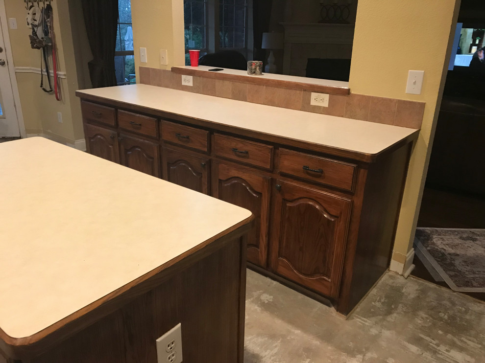 This is an example of a l-shaped kitchen pantry in Dallas with a single-bowl sink, shaker cabinets, white cabinets, quartz benchtops, beige splashback, ceramic splashback, stainless steel appliances, dark hardwood floors, with island, brown floor and white benchtop.