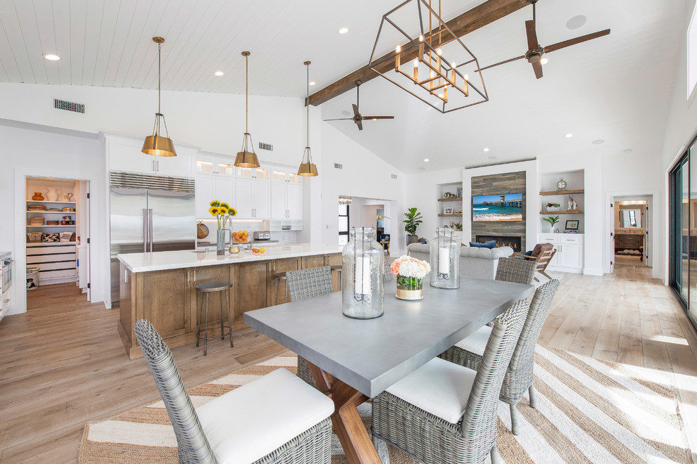 This is an example of a large country kitchen/dining combo in Orange County with white walls, medium hardwood floors, no fireplace, a wood fireplace surround and brown floor.