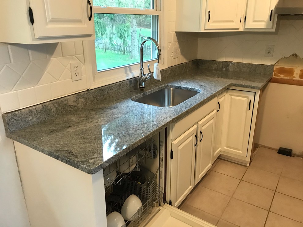 Small l-shaped ceramic tile and beige floor enclosed kitchen photo with raised-panel cabinets, white cabinets, granite countertops, white backsplash, subway tile backsplash, no island, gray countertops, an undermount sink and stainless steel appliances