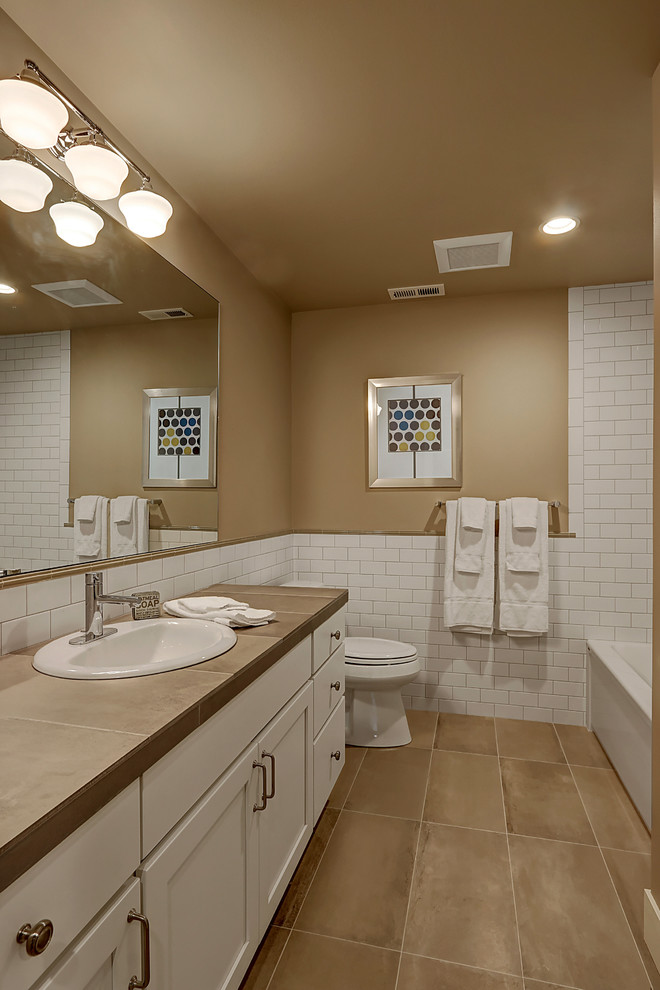 Mid-sized transitional bathroom in Seattle with shaker cabinets, white cabinets, an alcove tub, a shower/bathtub combo, white tile, subway tile, brown walls, porcelain floors, a drop-in sink and tile benchtops.