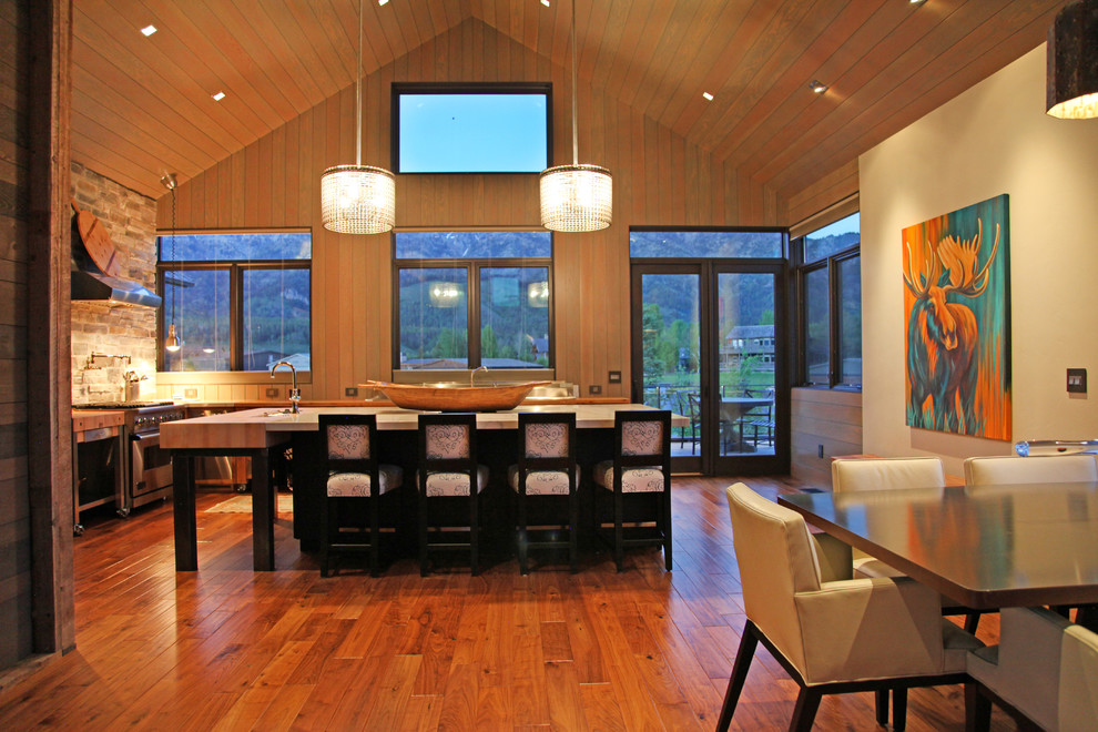 Mid-sized trendy l-shaped medium tone wood floor open concept kitchen photo with a drop-in sink, flat-panel cabinets, stainless steel cabinets, quartzite countertops, stainless steel appliances and an island
