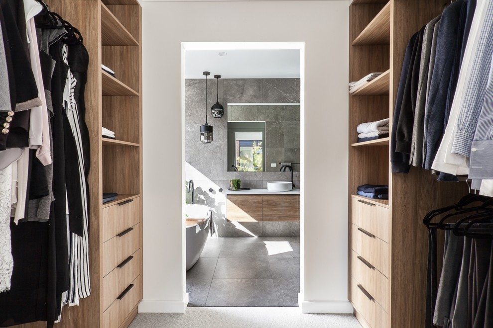 Design ideas for a small modern gender-neutral walk-in wardrobe in Melbourne with medium wood cabinets, carpet and grey floor.
