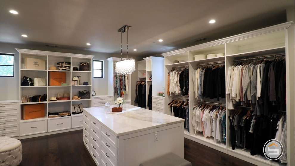 This is an example of a large mediterranean women's storage and wardrobe in Sacramento with flat-panel cabinets, white cabinets, medium hardwood floors and brown floor.