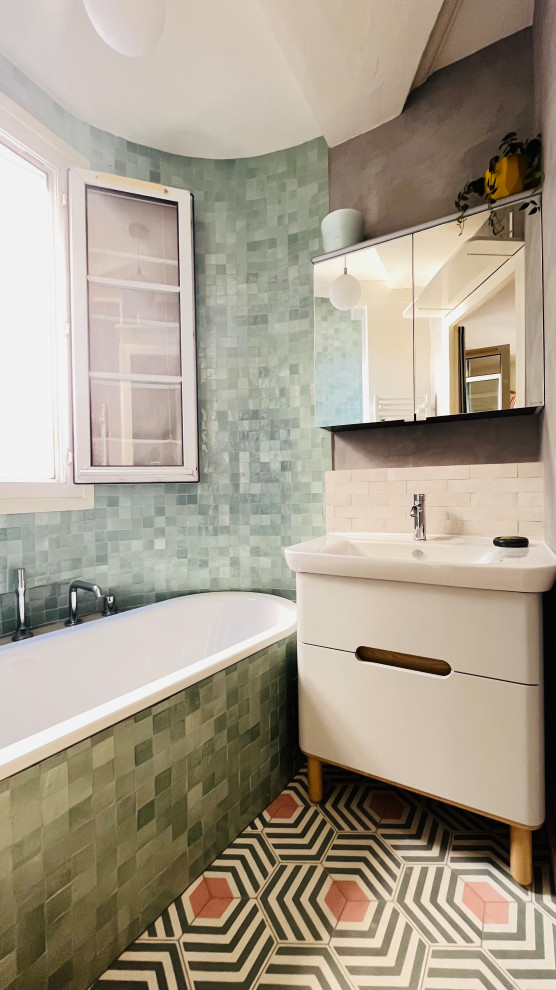 Modern inredning av ett litet badrum med dusch, med grön kakel, mosaik, cementgolv, ett avlångt handfat och rosa golv