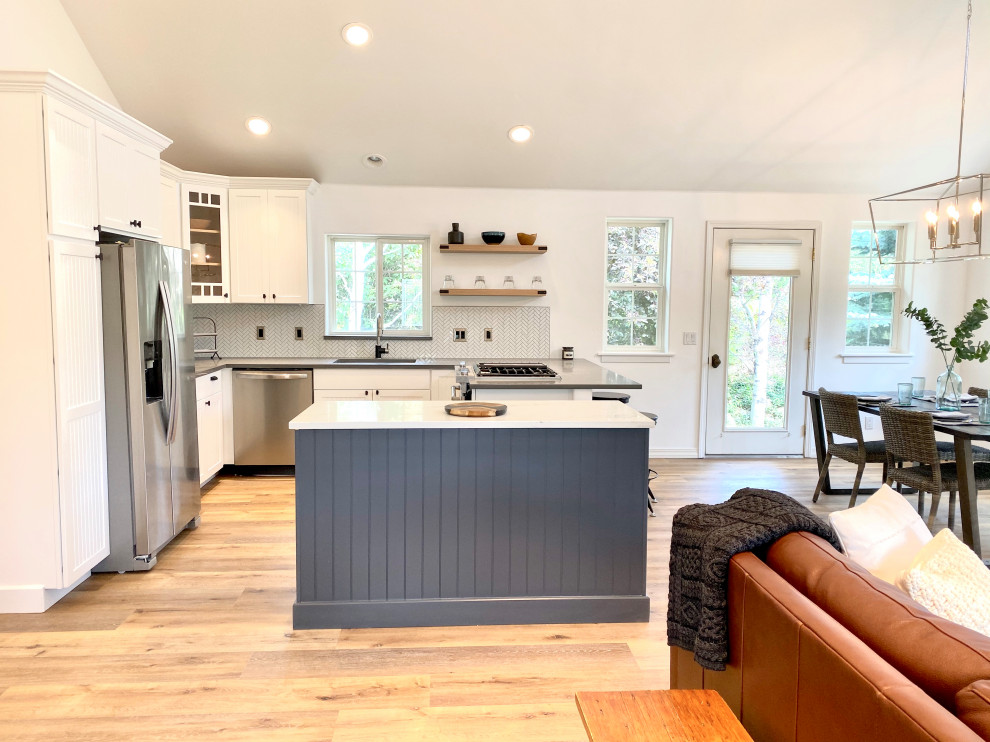 Inspiration for a mid-sized country u-shaped open plan kitchen in Denver with an undermount sink, shaker cabinets, white cabinets, quartz benchtops, white splashback, mosaic tile splashback, stainless steel appliances, medium hardwood floors, with island, grey benchtop and vaulted.