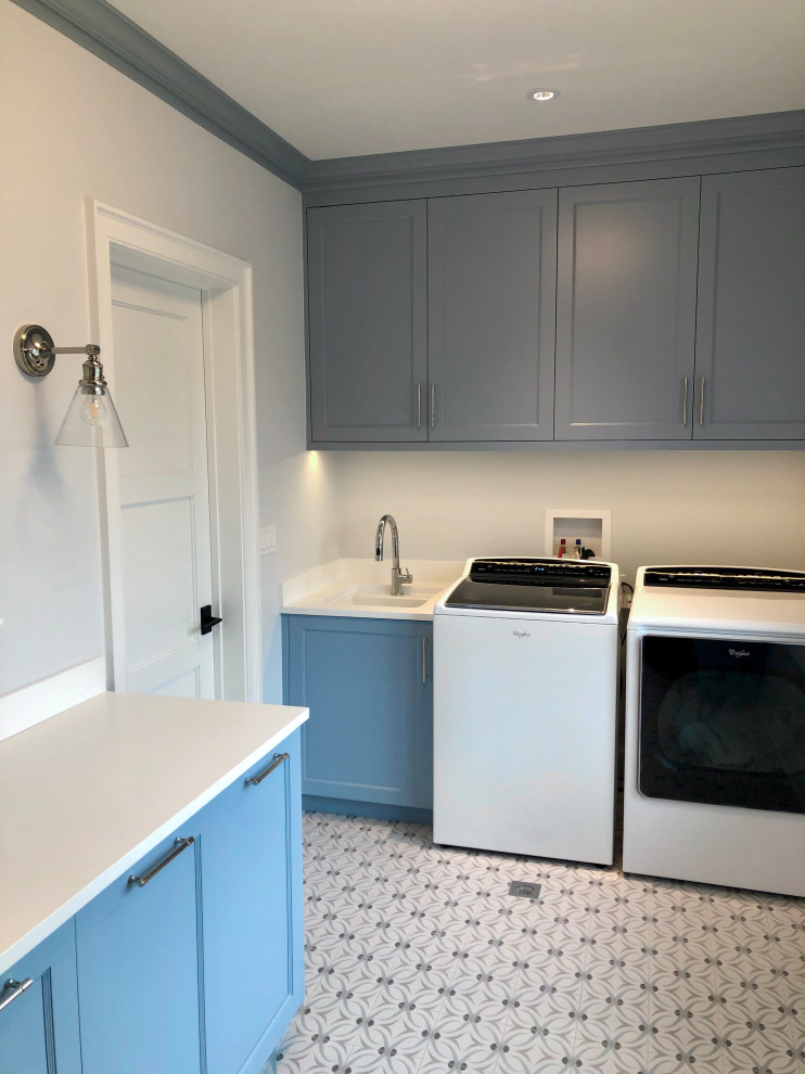 Inspiration for a mid-sized country l-shaped dedicated laundry room in Chicago with an undermount sink, recessed-panel cabinets, blue cabinets, quartz benchtops, white walls, ceramic floors, a side-by-side washer and dryer, blue floor and white benchtop.