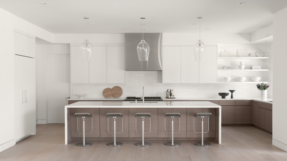 Photo of a modern u-shaped kitchen pantry in San Francisco with an undermount sink, flat-panel cabinets, medium wood cabinets, marble benchtops, white splashback, marble splashback, white appliances, light hardwood floors, with island, brown floor and white benchtop.