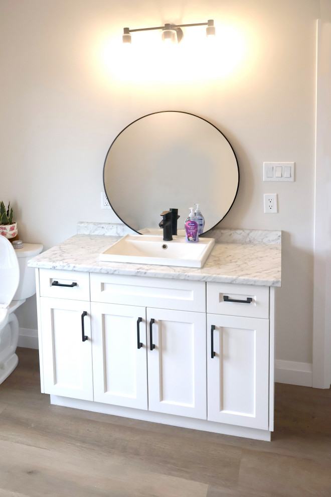 Свежая идея для дизайна: туалет среднего размера в стиле модернизм с фасадами с утопленной филенкой, белыми фасадами, унитазом-моноблоком, белыми стенами, светлым паркетным полом, консольной раковиной, мраморной столешницей, коричневым полом, разноцветной столешницей и подвесной тумбой - отличное фото интерьера