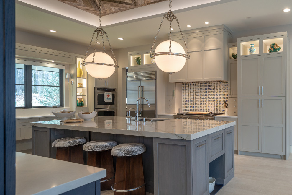 Inspiration for a transitional u-shaped gray floor kitchen remodel with an undermount sink, shaker cabinets, gray cabinets, multicolored backsplash, stainless steel appliances, an island and white countertops