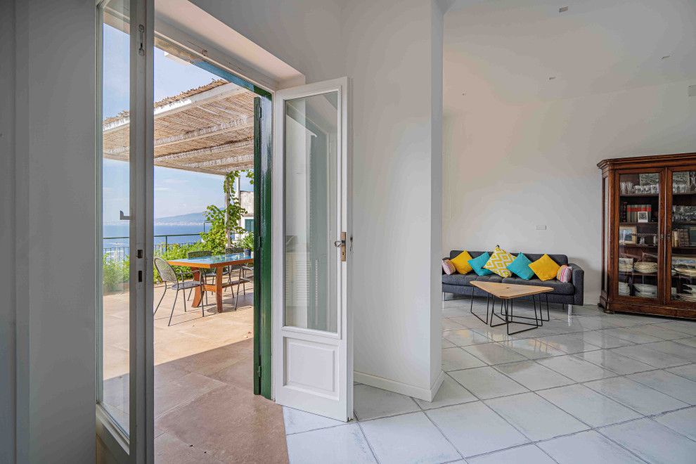 Стильный дизайн: гостиная комната в средиземноморском стиле с полом из керамической плитки, бирюзовым полом, белыми стенами и многоуровневым потолком - последний тренд