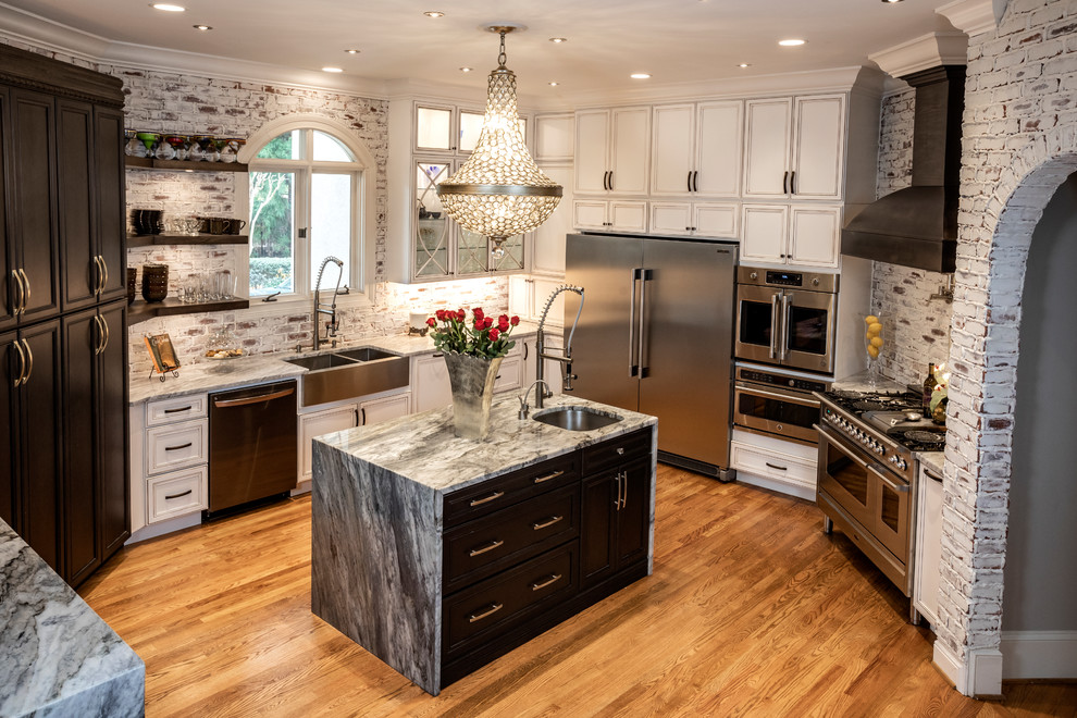 Large traditional open plan kitchen in Atlanta with a farmhouse sink, flat-panel cabinets, white cabinets, limestone benchtops, red splashback, brick splashback, stainless steel appliances, light hardwood floors, multiple islands, brown floor and grey benchtop.