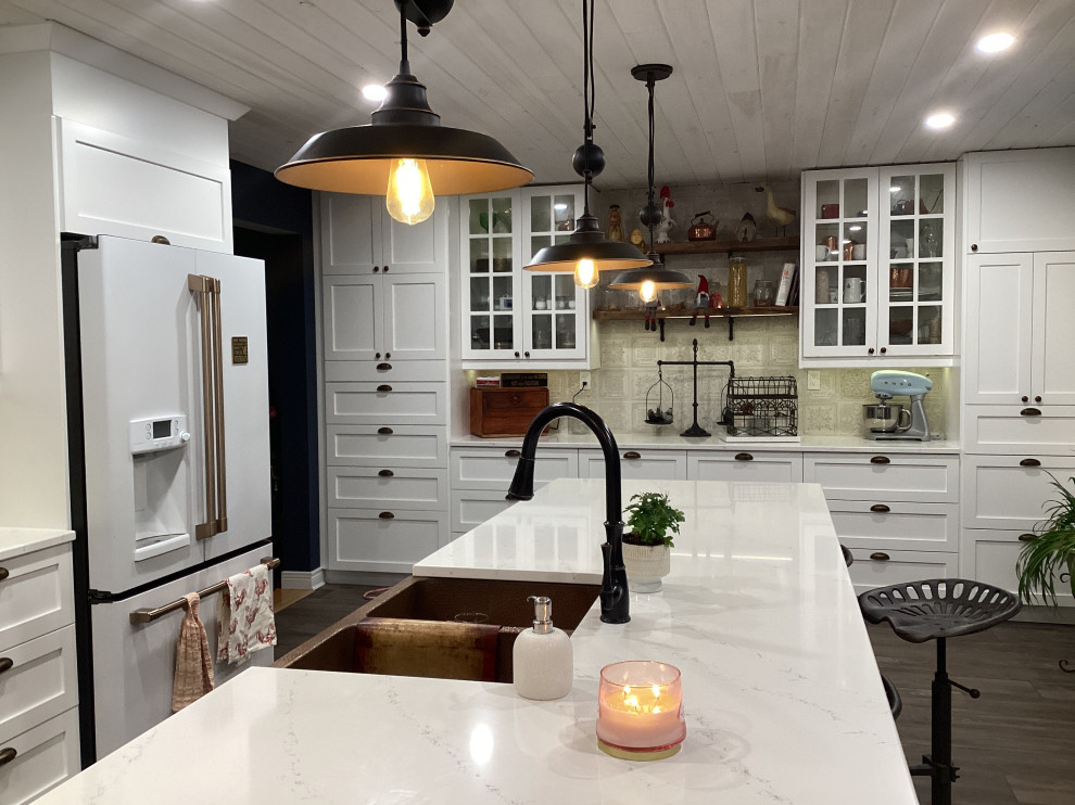 This is an example of a large country u-shaped eat-in kitchen in Other with an undermount sink, shaker cabinets, white cabinets, quartz benchtops, white splashback, ceramic splashback, white appliances, porcelain floors, with island, brown floor, white benchtop and timber.