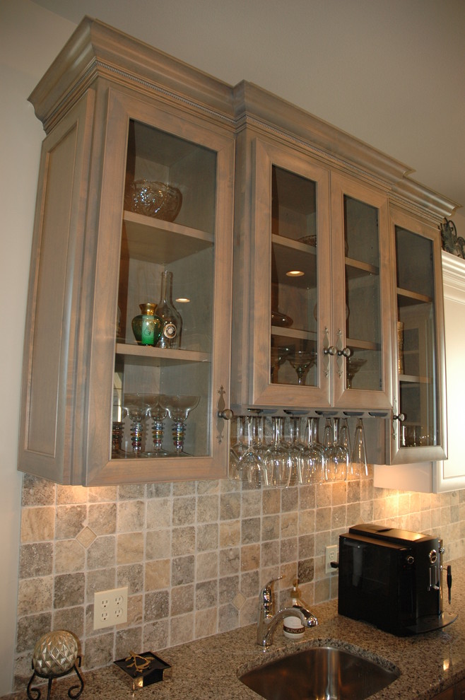 Example of a large transitional u-shaped medium tone wood floor kitchen pantry design with a farmhouse sink, flat-panel cabinets, white cabinets, granite countertops, brown backsplash, stone tile backsplash, paneled appliances and an island