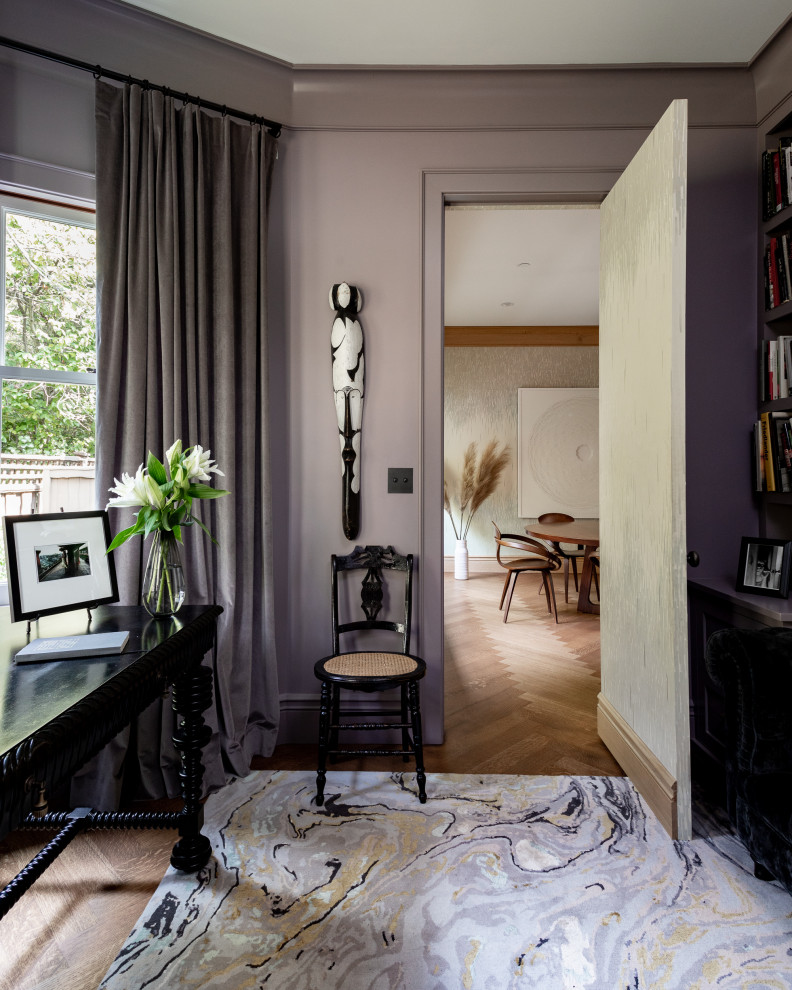Großes Uriges Lesezimmer mit lila Wandfarbe, braunem Holzboden, freistehendem Schreibtisch und braunem Boden in Sonstige