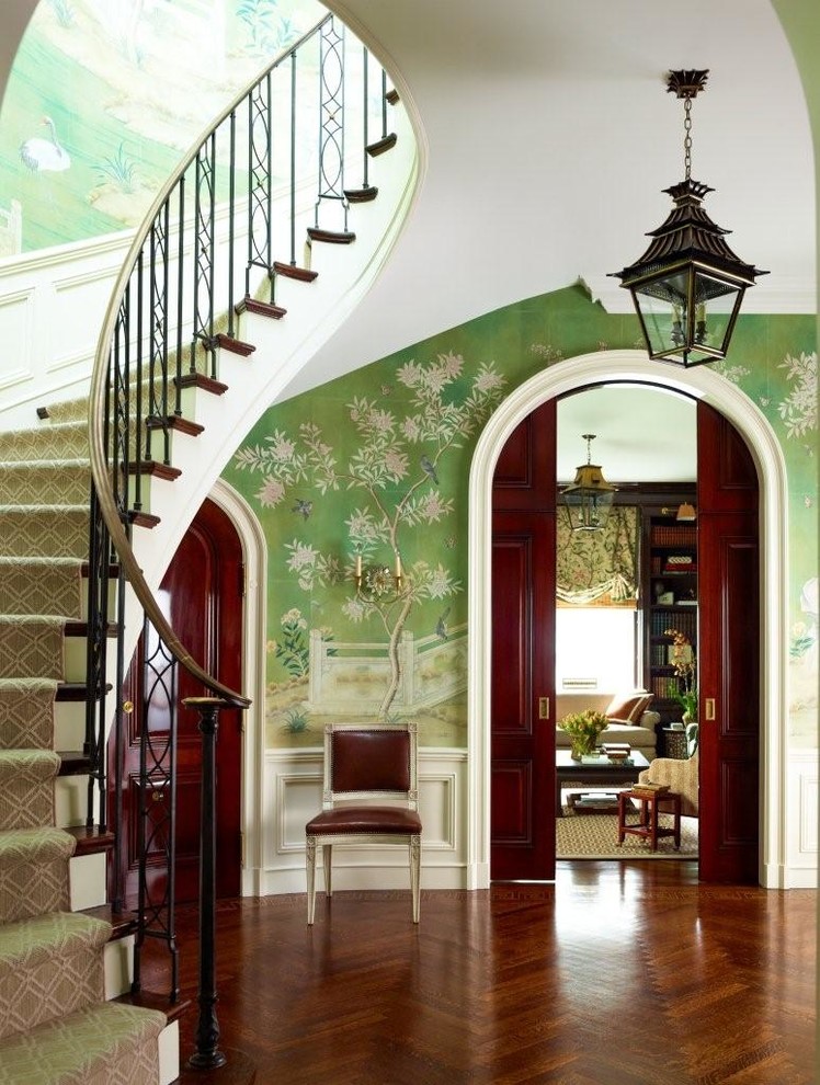 Photo of a traditional foyer in New York with green walls, medium hardwood floors, a dark wood front door and brown floor.