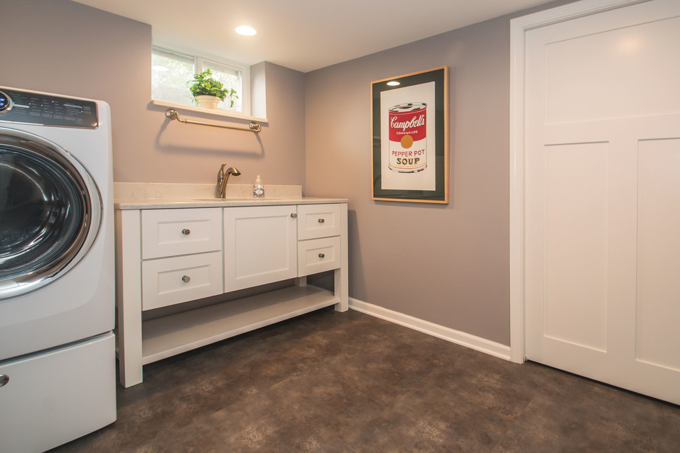 This is an example of a mid-sized beach style single-wall dedicated laundry room in Milwaukee with an undermount sink, shaker cabinets, white cabinets, quartz benchtops, grey walls, vinyl floors, a side-by-side washer and dryer, grey floor and white benchtop.