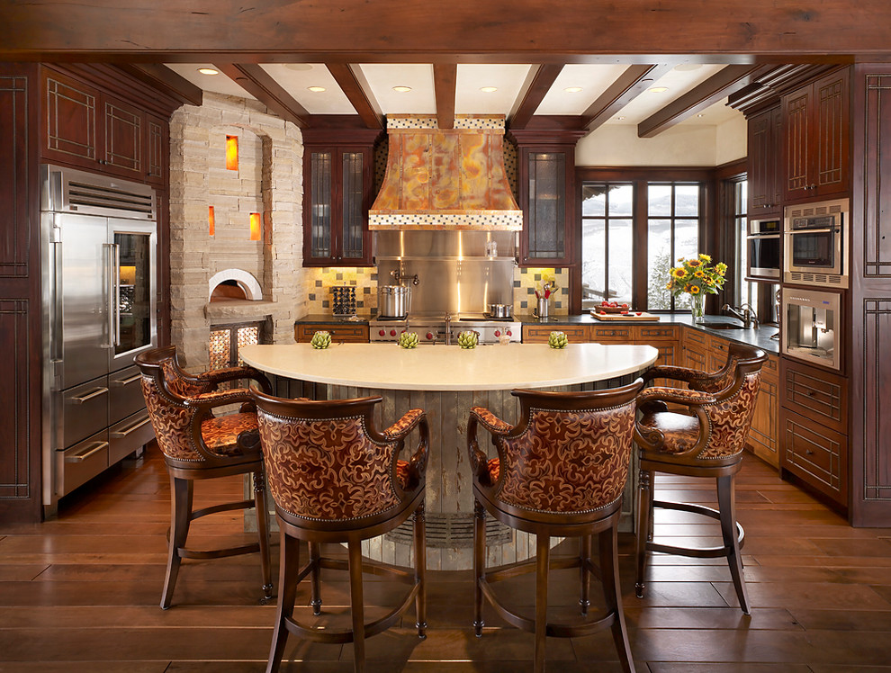 Example of a large mountain style u-shaped kitchen design in Denver with dark wood cabinets, stainless steel appliances and an island