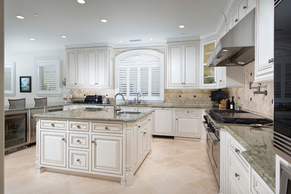 Design ideas for a large traditional u-shaped eat-in kitchen in Orange County with an undermount sink, raised-panel cabinets, white cabinets, granite benchtops, beige splashback, stone tile splashback, stainless steel appliances, marble floors, with island and beige floor.