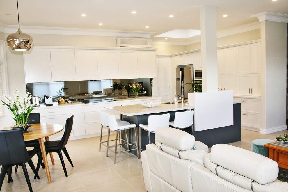 Photo of a large transitional l-shaped eat-in kitchen in Sydney with a drop-in sink, shaker cabinets, white cabinets, quartz benchtops, grey splashback, glass sheet splashback, stainless steel appliances, ceramic floors and with island.