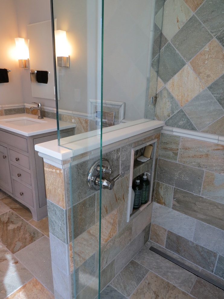 Photo of a mid-sized beach style master bathroom in Portland Maine with furniture-like cabinets, grey cabinets, a freestanding tub, a curbless shower, a wall-mount toilet, multi-coloured tile, stone tile, multi-coloured walls, pebble tile floors, an undermount sink and engineered quartz benchtops.