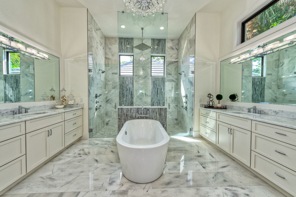 Inspiration for a master bathroom in Miami with recessed-panel cabinets, white cabinets, a freestanding tub, a double shower, gray tile, white walls, an undermount sink, grey floor, a hinged shower door and grey benchtops.