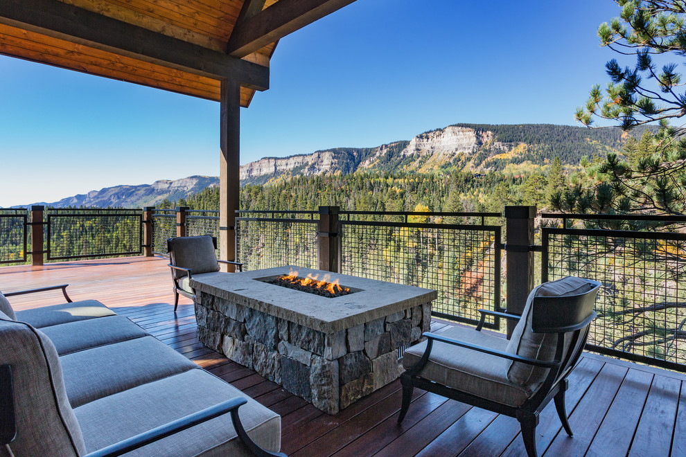Deck - large rustic backyard deck idea with a fire pit and a roof extension