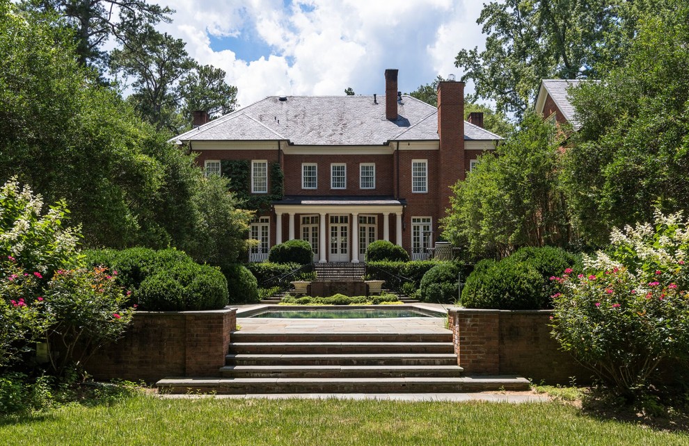 Traditional two-storey brick red house exterior in Atlanta with a hip roof and a shingle roof.