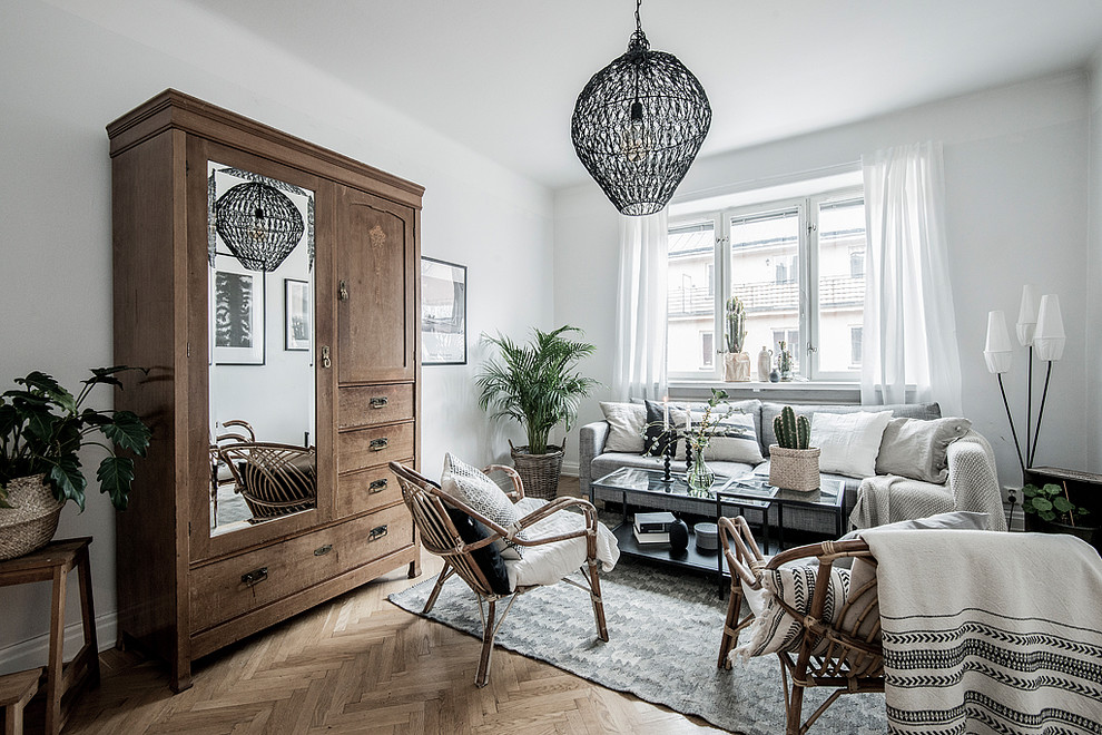 Photo of a mid-sized scandinavian enclosed living room in Stockholm with white walls, medium hardwood floors, no fireplace and brown floor.