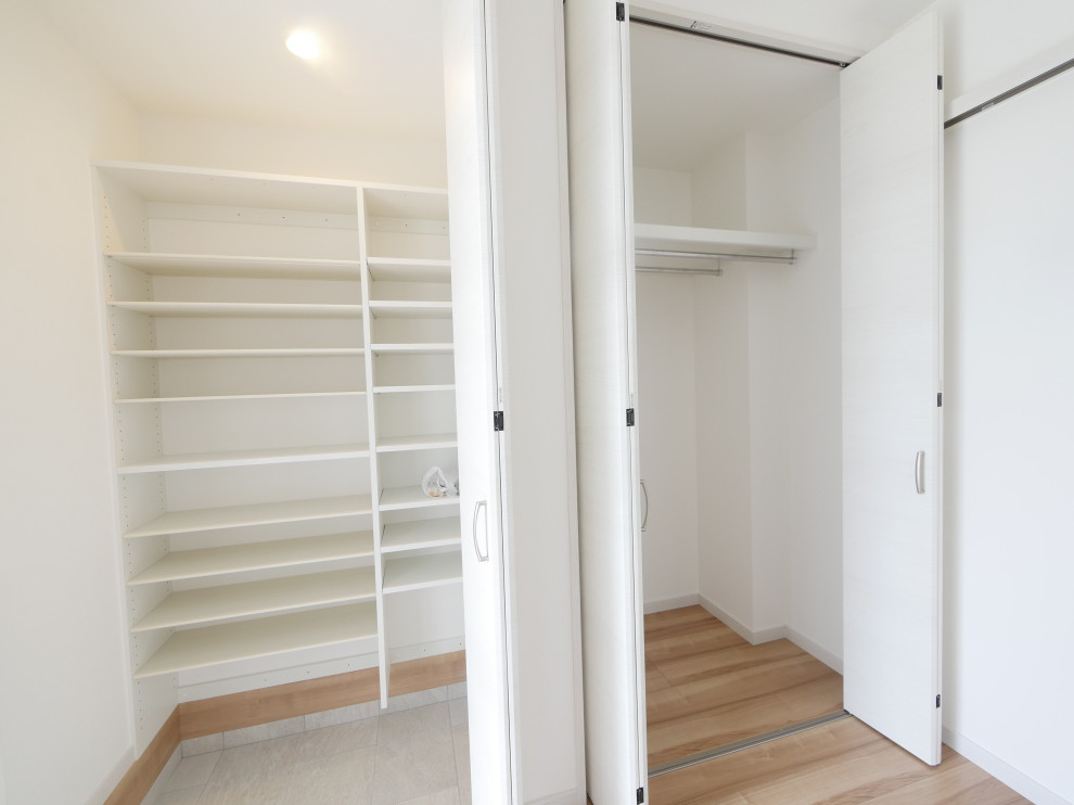 Imagen de armario y vestidor campestre con puertas de armario blancas, suelo de contrachapado, suelo beige y papel pintado