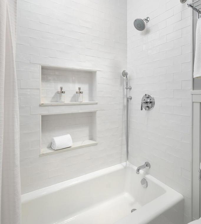 Inredning av ett lantligt litet badrum, med ett badkar i en alkov, en dusch/badkar-kombination, vit kakel, keramikplattor, grå väggar och mosaikgolv