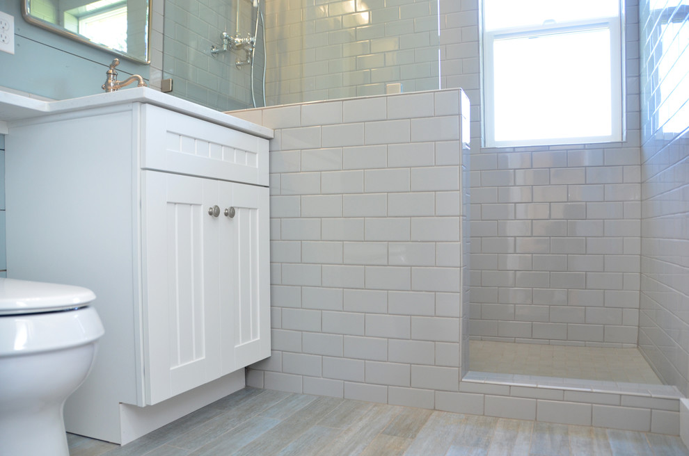 Photo of a small country 3/4 bathroom in Seattle with beaded inset cabinets, white cabinets, an open shower, gray tile, subway tile, blue walls, ceramic floors, an undermount sink and engineered quartz benchtops.