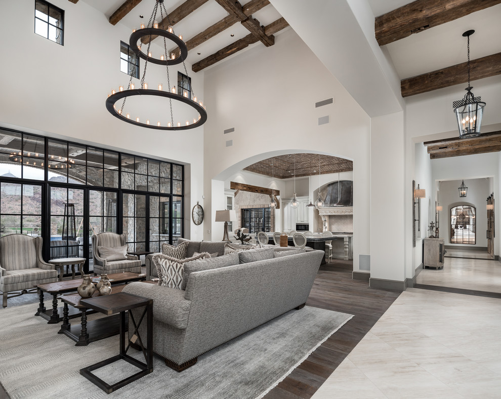 This is an example of an expansive industrial open concept family room in Phoenix with beige walls, dark hardwood floors, a standard fireplace, a stone fireplace surround, a wall-mounted tv and multi-coloured floor.