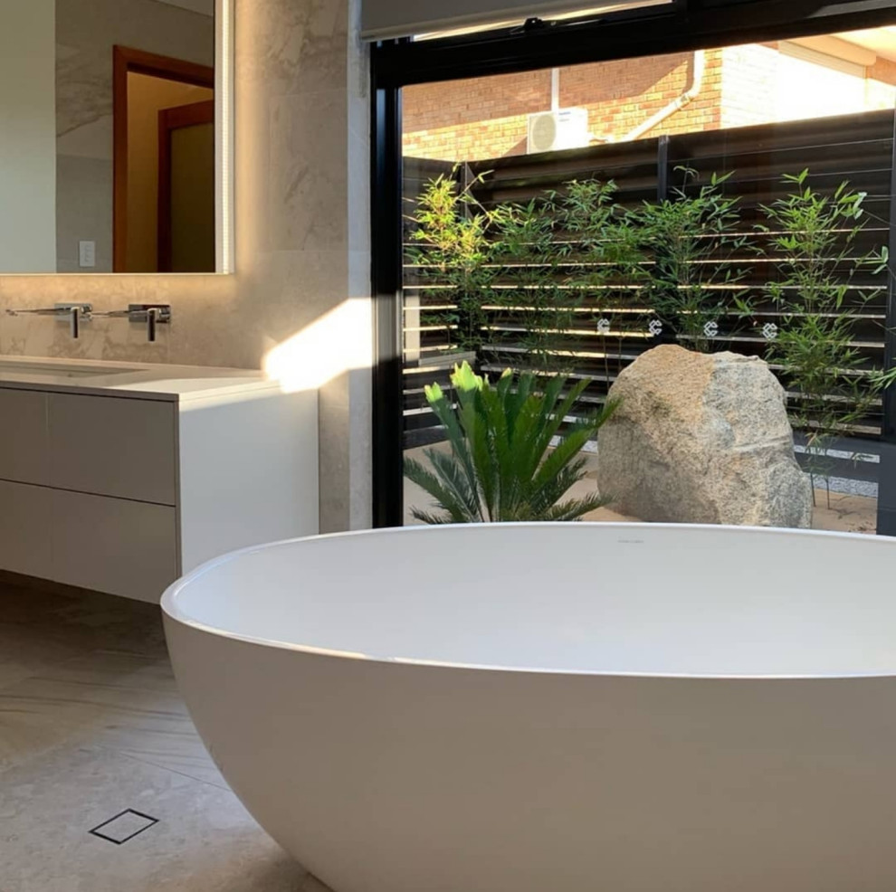 Contemporary master bathroom in Perth with marble benchtops, a floating vanity, flat-panel cabinets, white cabinets, a freestanding tub, gray tile, marble, white benchtops, a single vanity, grey walls, ceramic floors, an undermount sink and grey floor.
