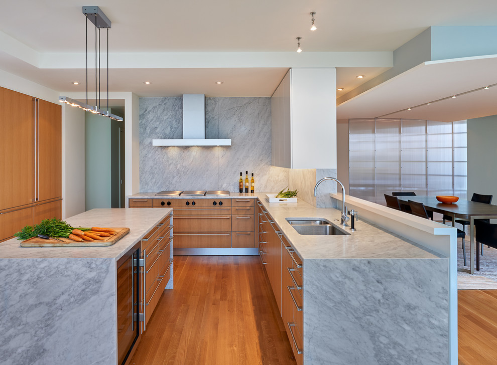 This is an example of a contemporary eat-in kitchen in DC Metro with a double-bowl sink, flat-panel cabinets, medium wood cabinets, marble benchtops, panelled appliances, medium hardwood floors, with island and grey splashback.