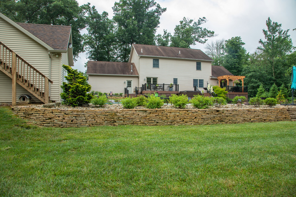 Design ideas for a mid-sized transitional drought-tolerant and partial sun backyard brick retaining wall landscape for summer.