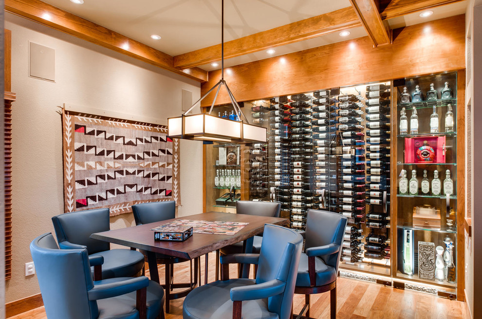 This is an example of a wine cellar in Denver with medium hardwood floors, display racks and orange floor.