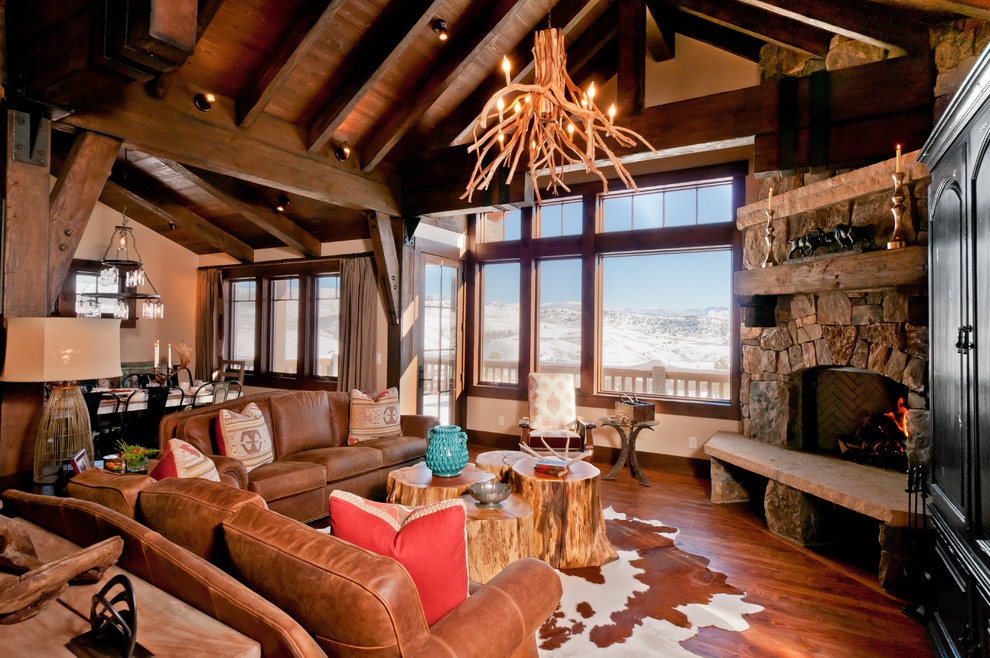 Mid-sized country formal open concept living room in Denver with beige walls, medium hardwood floors, a corner fireplace, a stone fireplace surround and a concealed tv.