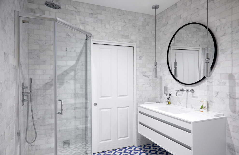 This is an example of a mid-sized contemporary master bathroom in London with flat-panel cabinets, white cabinets, a freestanding tub, a corner shower, a one-piece toilet, gray tile, porcelain tile, ceramic floors, a drop-in sink, granite benchtops, blue floor and a hinged shower door.