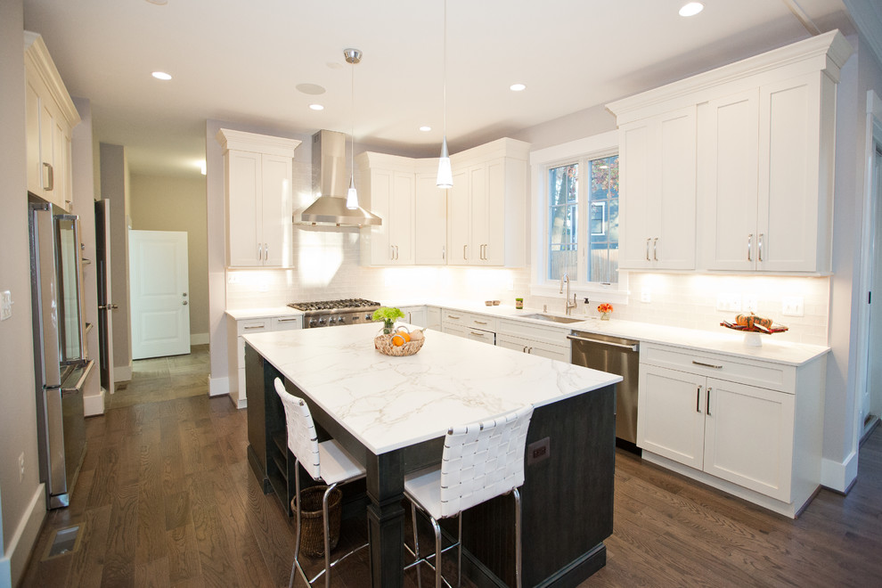 This is an example of a transitional kitchen in DC Metro with recessed-panel cabinets, white cabinets, white splashback, stainless steel appliances, dark hardwood floors and with island.