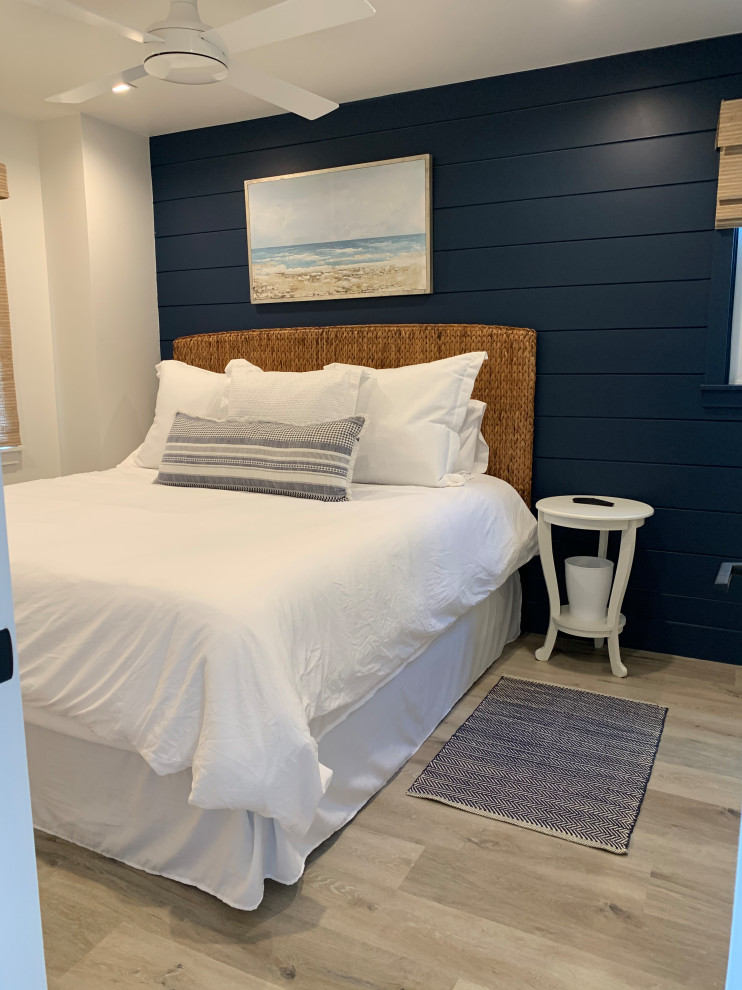 Kleines Maritimes Gästezimmer mit blauer Wandfarbe, Vinylboden, beigem Boden und Holzdielenwänden in Orange County