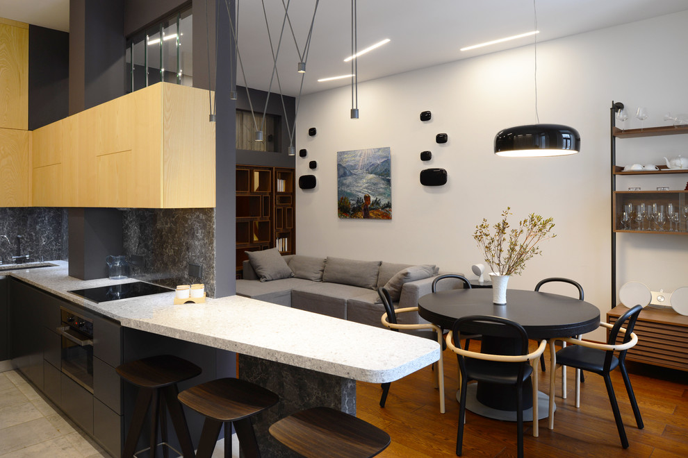 Design ideas for a small contemporary l-shaped open plan kitchen in Moscow with an undermount sink, flat-panel cabinets, solid surface benchtops, black appliances, porcelain floors and black splashback.