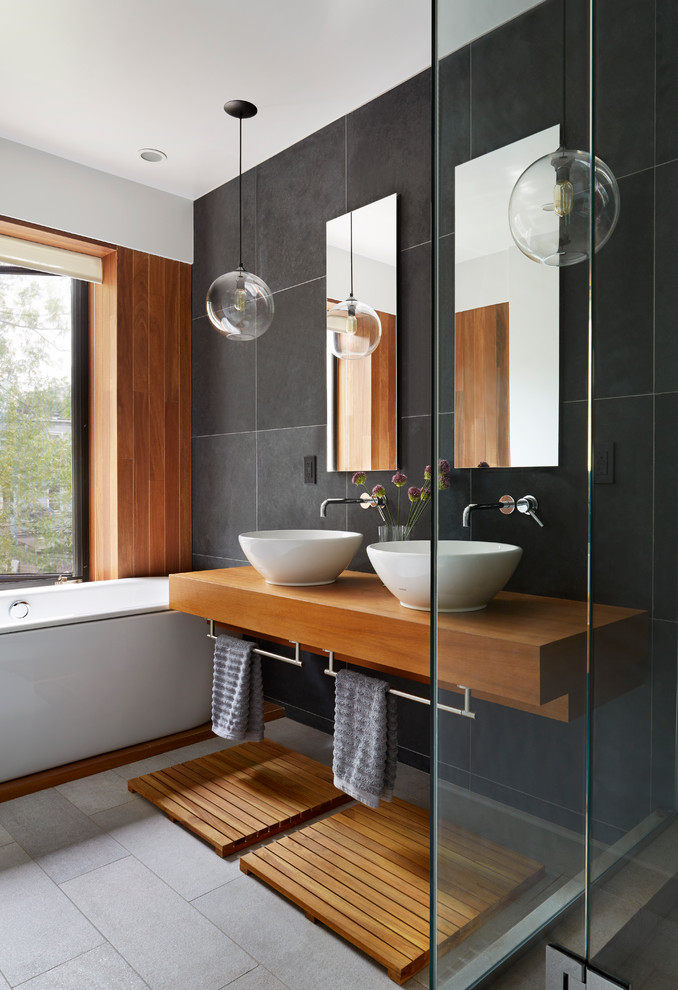 Inspiration for a contemporary bathroom in New York with a vessel sink, wood benchtops, a drop-in tub, black tile, slate and brown benchtops.