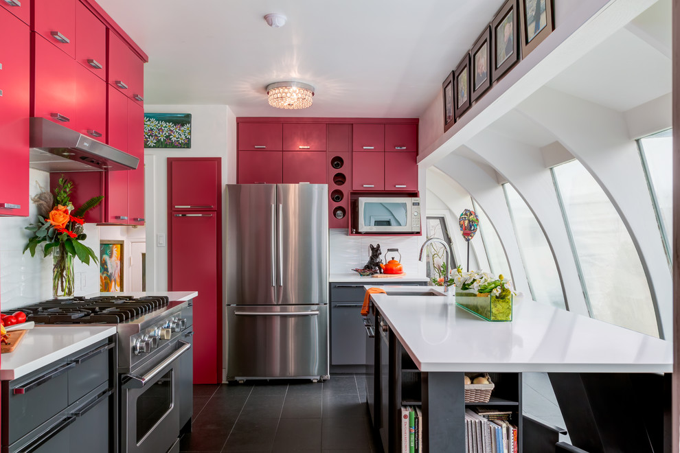 Example of a transitional l-shaped kitchen design in Calgary with an undermount sink, flat-panel cabinets, red cabinets, white backsplash, stainless steel appliances and an island