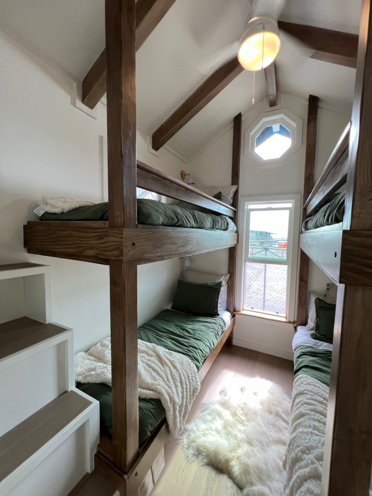 Immagine di una piccola cameretta per bambini da 4 a 10 anni country con pareti bianche, parquet chiaro, pavimento beige e travi a vista