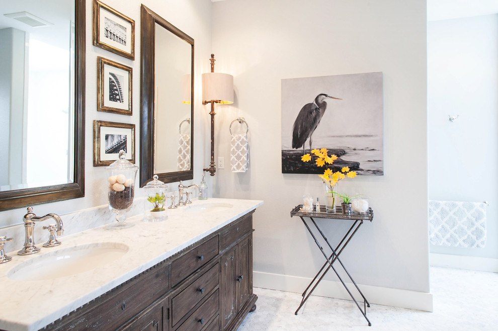 This is an example of a transitional bathroom in Portland with an undermount sink, furniture-like cabinets, distressed cabinets, marble benchtops, a freestanding tub, a two-piece toilet, gray tile and stone tile.