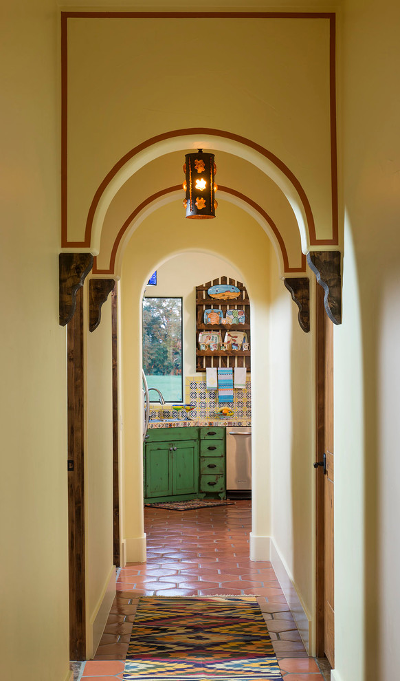 Photo of a large hallway in San Diego with yellow walls and terra-cotta floors.