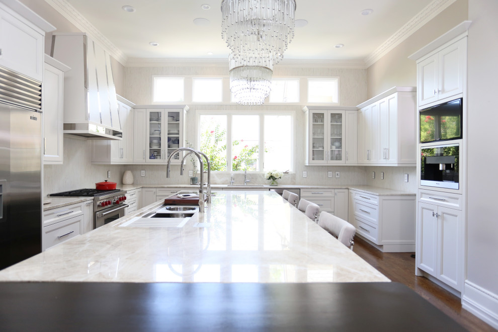 Example of a huge transitional medium tone wood floor and brown floor eat-in kitchen design with an undermount sink, recessed-panel cabinets, white cabinets, quartzite countertops, white backsplash, ceramic backsplash, stainless steel appliances, an island and white countertops